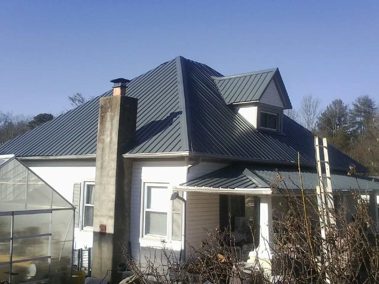 Dark blue standing seam metal roof on a white farmhouse with dormer — Slate & Tile Roof Repair by Roofing Brothers in Valles Mines