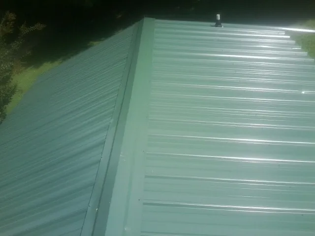 New green metal panels meeting at the ridge of a roof — Flat Roof Repair work by our crew in Valles Mines