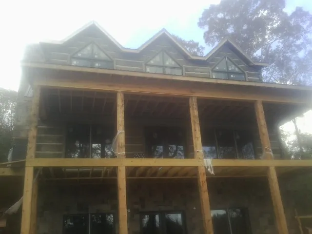 Dormers and porch framing on a large log home under construction — Roof Coating work by our crew in Valles Mines