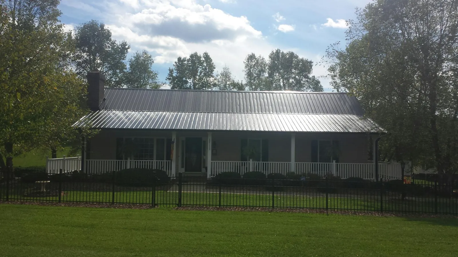 Gray metal roof on a brick ranch with a full width front porch — Gutter Guard Installation work by our crew in Valles Mines