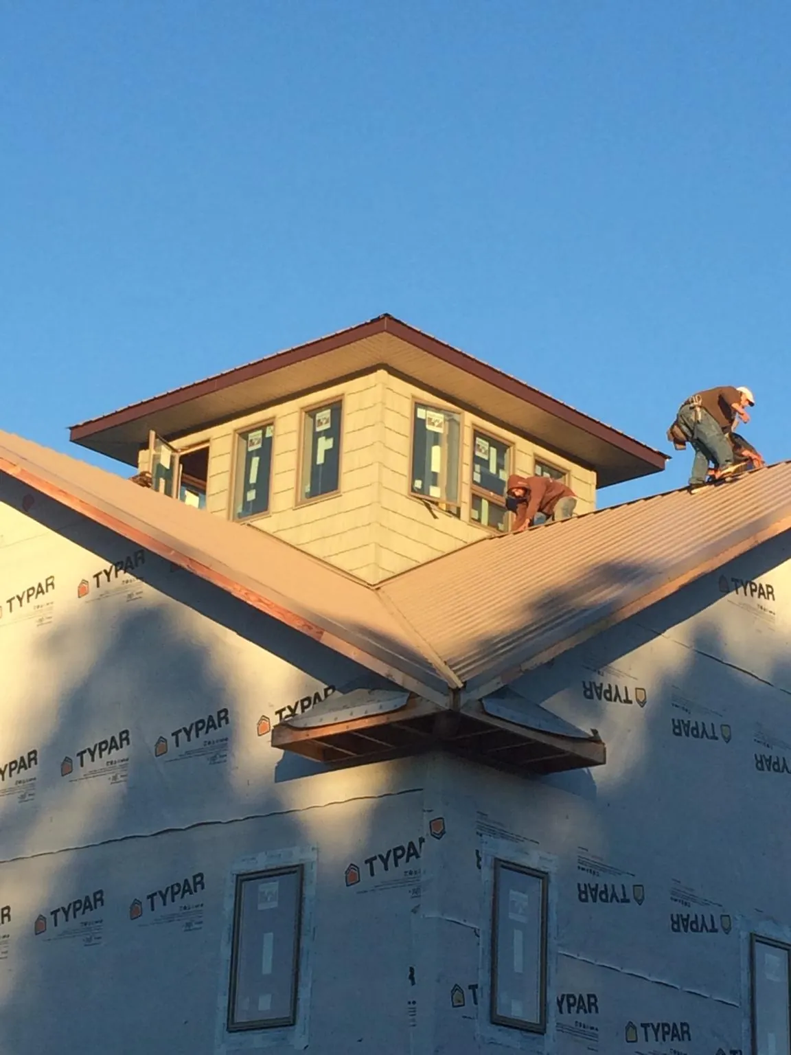 Roofers working around a rooftop cupola on a new metal roof at sunset — Roof Waterproofing in Valles Mines by Roofing Brothers